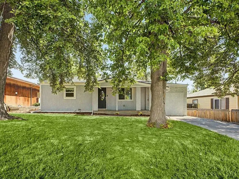 Single-story home with a large shade tree at 1140 South Wolff Street in Denver, Colorado.